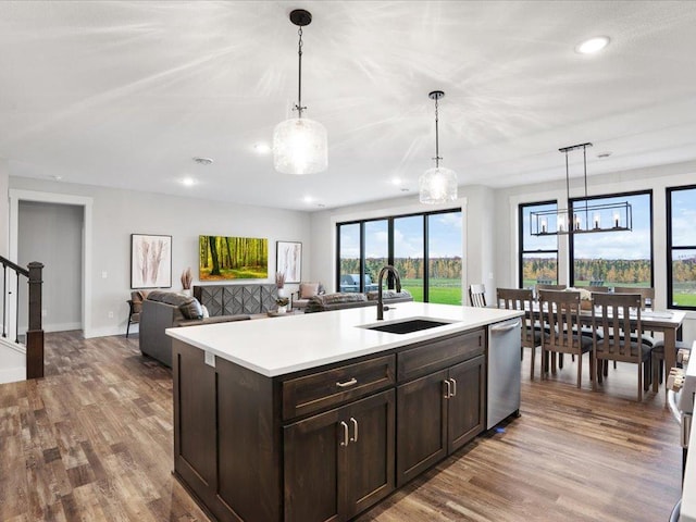 kitchen with dark brown cabinetry, sink, decorative light fixtures, dishwasher, and an island with sink