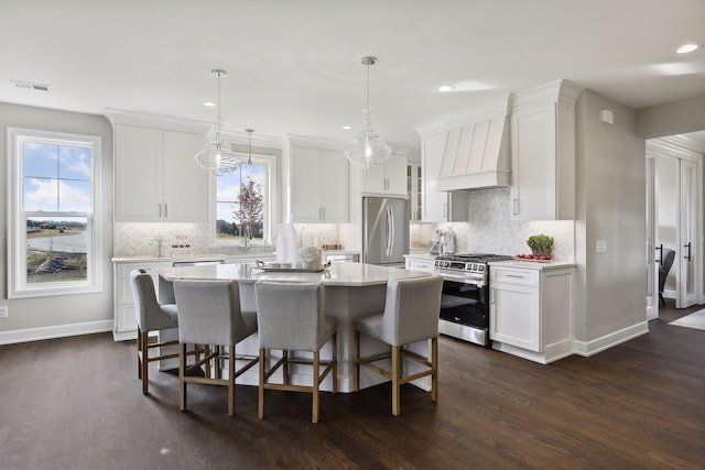 kitchen with white cabinetry, decorative light fixtures, stainless steel appliances, and a center island