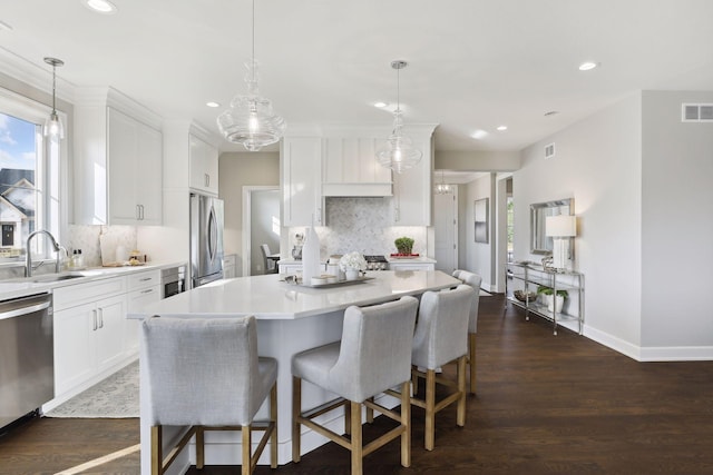 kitchen featuring sink, decorative light fixtures, a kitchen island, stainless steel appliances, and white cabinets