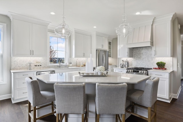 kitchen with custom exhaust hood, a center island, white cabinets, and appliances with stainless steel finishes