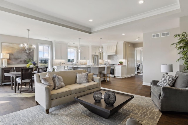 living room with crown molding, dark hardwood / wood-style floors, a chandelier, and a tray ceiling