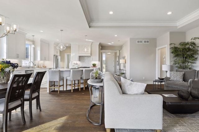 living room with ornamental molding, dark hardwood / wood-style floors, sink, and a tray ceiling