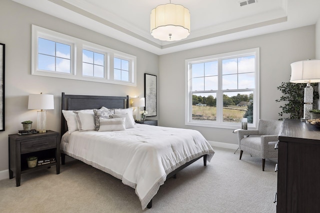 bedroom with light carpet, multiple windows, and a raised ceiling