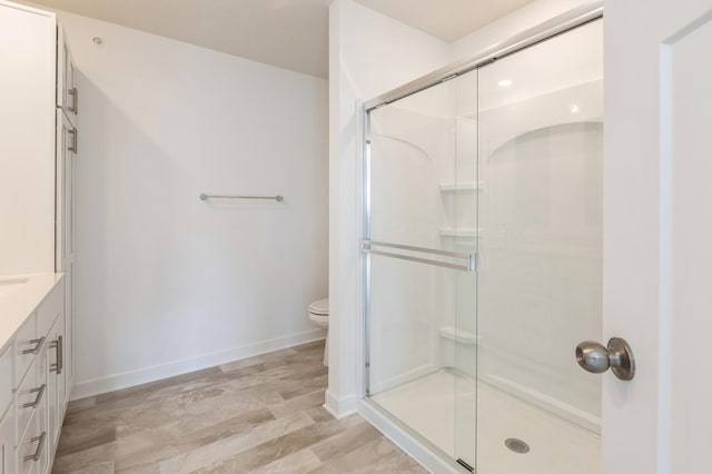 bathroom featuring hardwood / wood-style flooring, vanity, toilet, and a shower with door