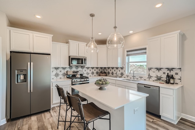 kitchen with white cabinetry, stainless steel appliances, a center island, and sink