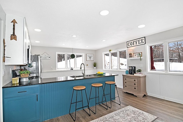 kitchen featuring appliances with stainless steel finishes, a kitchen breakfast bar, wood finished floors, a peninsula, and a sink