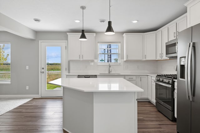 kitchen with pendant lighting, white cabinetry, sink, a center island, and stainless steel appliances