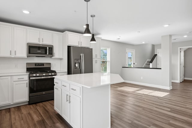 kitchen featuring stainless steel appliances, decorative light fixtures, a kitchen island, and white cabinets