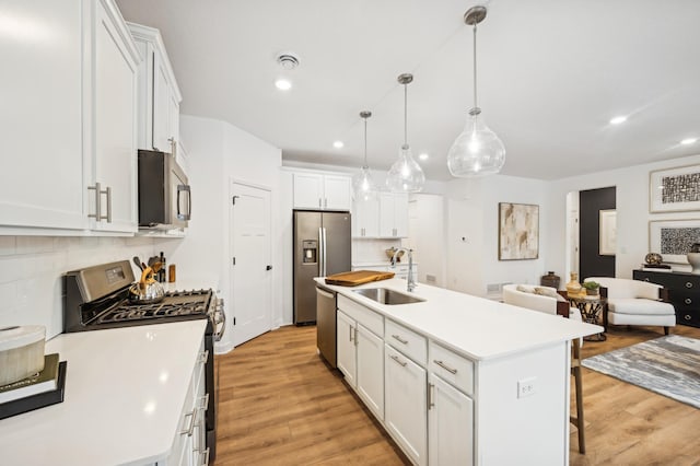 kitchen with an island with sink, appliances with stainless steel finishes, sink, and white cabinets