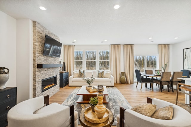 living room with a fireplace, light hardwood / wood-style flooring, and a textured ceiling