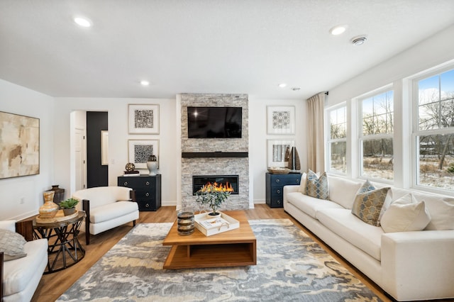 living room featuring a stone fireplace and hardwood / wood-style floors