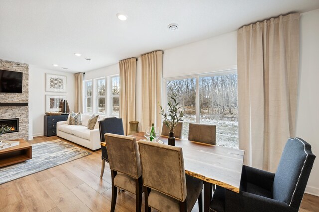 dining area featuring a stone fireplace and light hardwood / wood-style floors