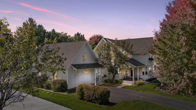 view of front of home with a garage, driveway, a front yard, and roof with shingles