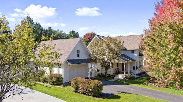 view of front of home featuring aphalt driveway, an attached garage, a front lawn, and a shingled roof