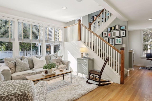 living area featuring stairway, baseboards, and light wood-type flooring