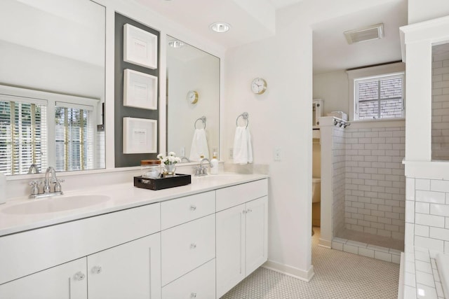 bathroom with tile patterned flooring, double vanity, visible vents, and a sink