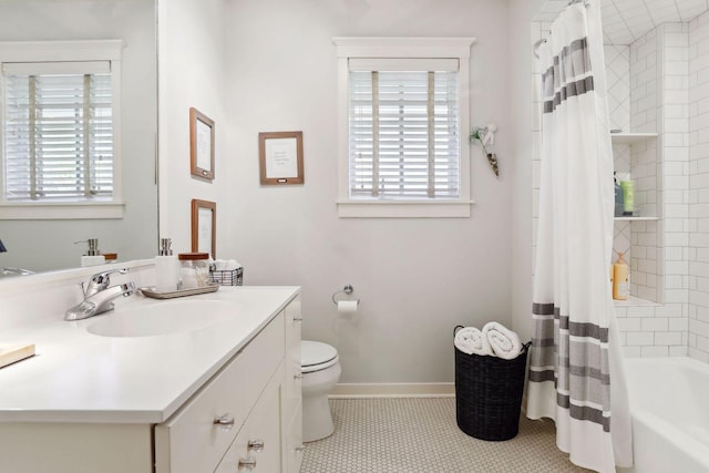 bathroom with baseboards, toilet, a healthy amount of sunlight, and vanity