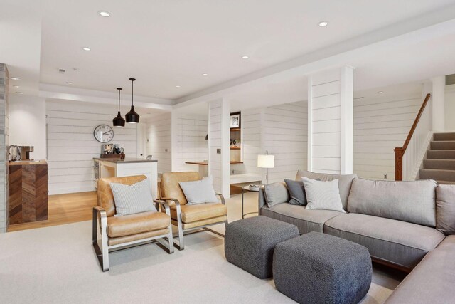 living area with wood walls, stairs, a tray ceiling, recessed lighting, and light wood-style floors