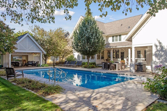 pool with outdoor lounge area, a patio area, and a grill