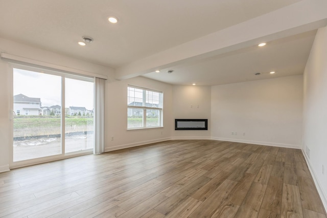 unfurnished living room featuring beam ceiling and light hardwood / wood-style flooring