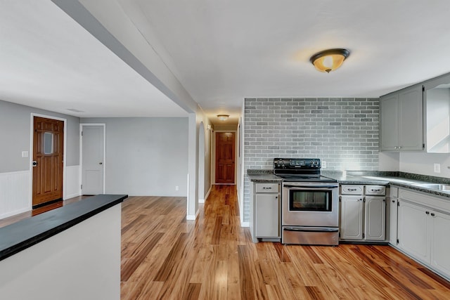 kitchen with stainless steel electric range oven, sink, gray cabinetry, and light hardwood / wood-style flooring