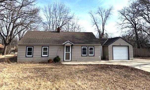 ranch-style home featuring fence, concrete driveway, roof with shingles, a chimney, and an attached garage