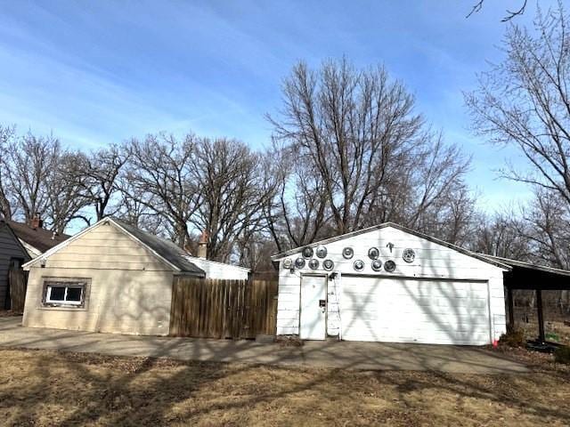 view of outbuilding featuring a garage, an outdoor structure, driveway, and fence