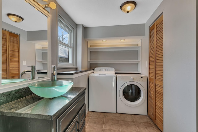 clothes washing area with light tile patterned floors, laundry area, separate washer and dryer, and a sink