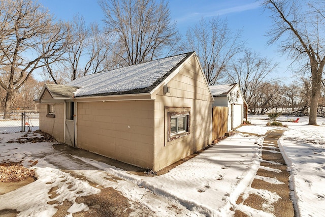 view of snowy exterior featuring concrete block siding and fence