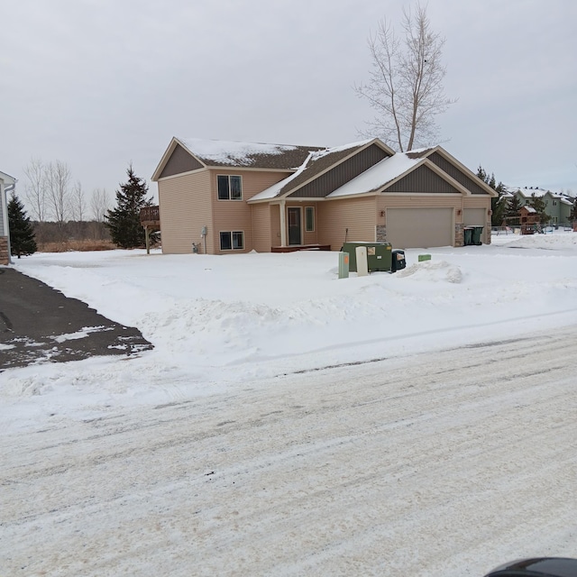 snow covered house featuring a garage