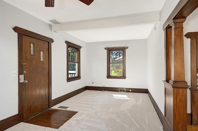 foyer featuring beam ceiling, carpet floors, and ornate columns