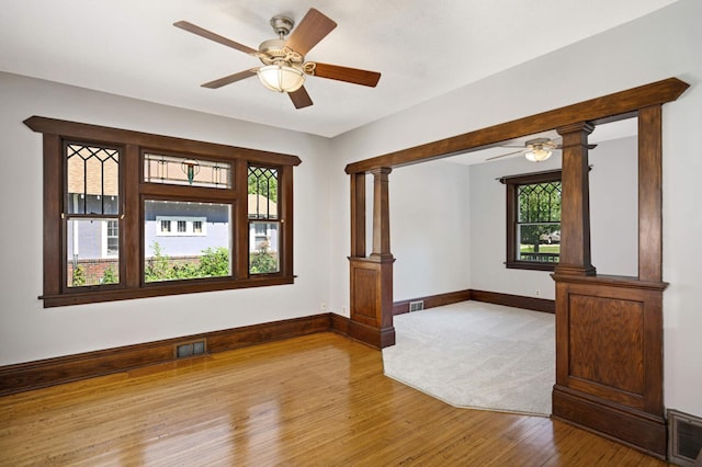 unfurnished living room with light hardwood / wood-style flooring, decorative columns, and ceiling fan