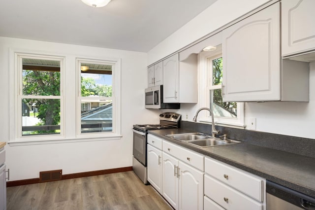 kitchen with white cabinetry, appliances with stainless steel finishes, sink, and light hardwood / wood-style flooring