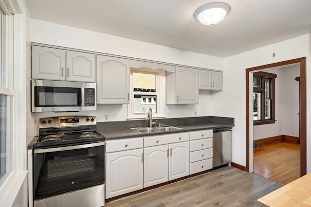 kitchen with white cabinets, stainless steel appliances, sink, and light wood-type flooring