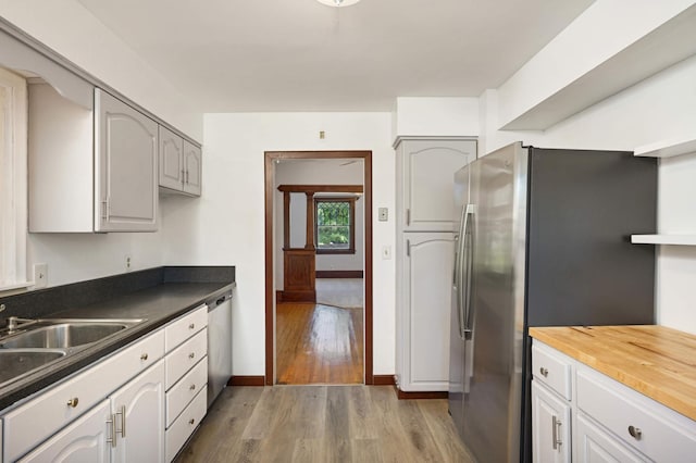 kitchen with appliances with stainless steel finishes, sink, hardwood / wood-style floors, and wood counters