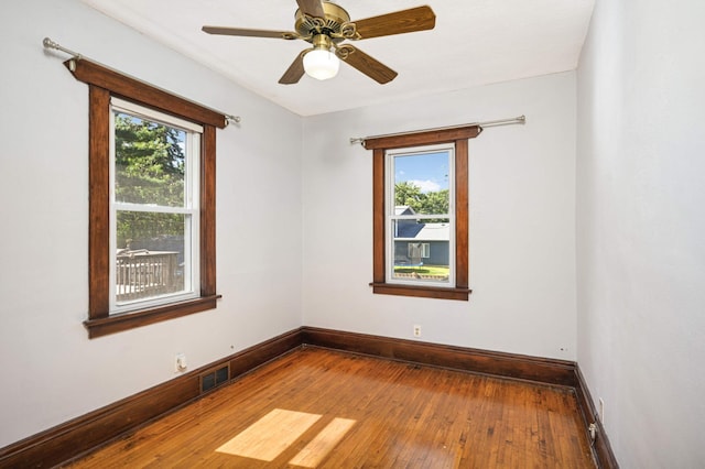 empty room featuring ceiling fan, a healthy amount of sunlight, and wood-type flooring