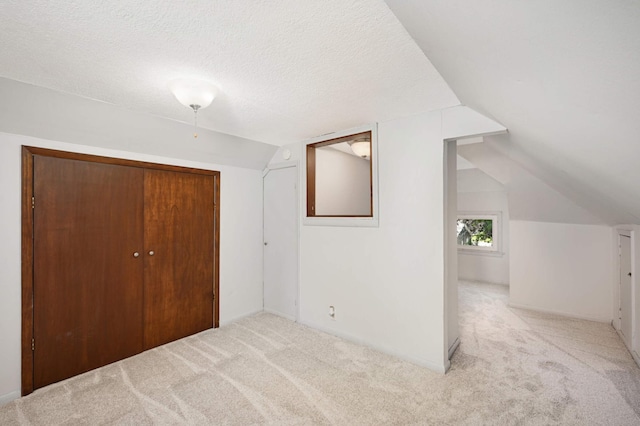 bonus room with vaulted ceiling, light carpet, and a textured ceiling