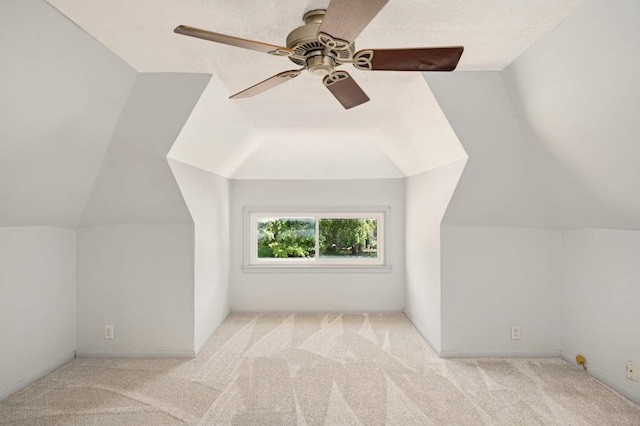 additional living space with ceiling fan, lofted ceiling, light carpet, and a textured ceiling