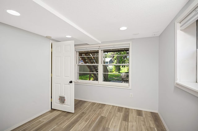 unfurnished room featuring a textured ceiling and light wood-type flooring