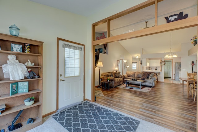 foyer with lofted ceiling, a wealth of natural light, a chandelier, and wood-type flooring