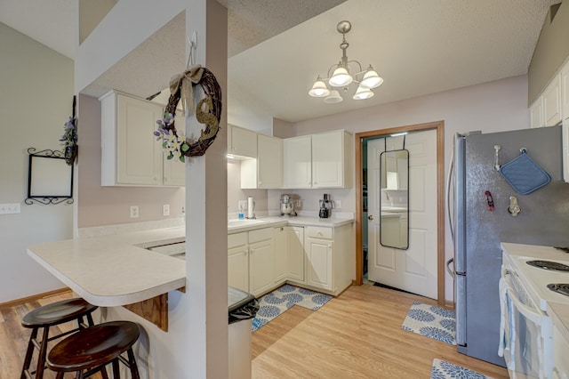 kitchen featuring pendant lighting, white cabinets, kitchen peninsula, and white range with electric stovetop