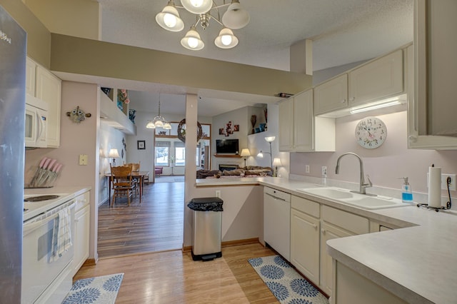 kitchen with pendant lighting, sink, a chandelier, and white appliances