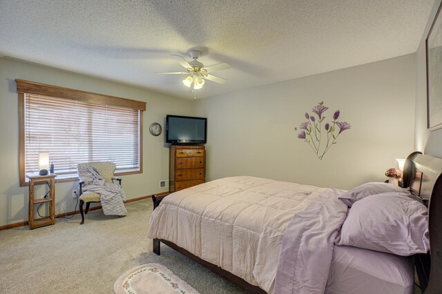 bedroom with ceiling fan, light colored carpet, and a textured ceiling