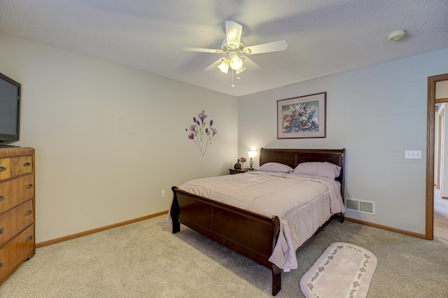 bedroom featuring light colored carpet, a textured ceiling, and ceiling fan