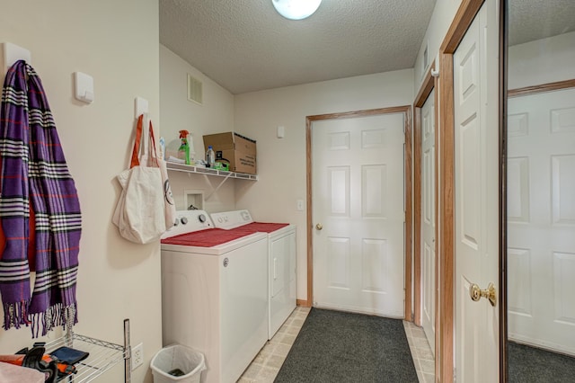 washroom with washing machine and dryer and a textured ceiling