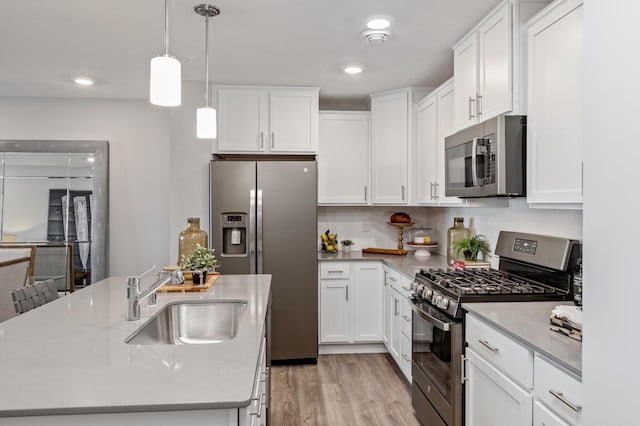 kitchen featuring white cabinetry, sink, stainless steel appliances, and hanging light fixtures