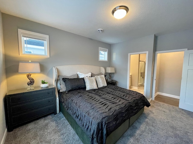 carpeted bedroom with a textured ceiling and ensuite bath