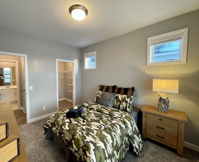 carpeted bedroom with sink, a walk in closet, and a textured ceiling