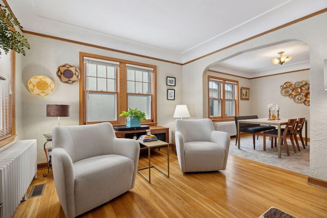 living room featuring crown molding, radiator heating unit, and light wood-type flooring