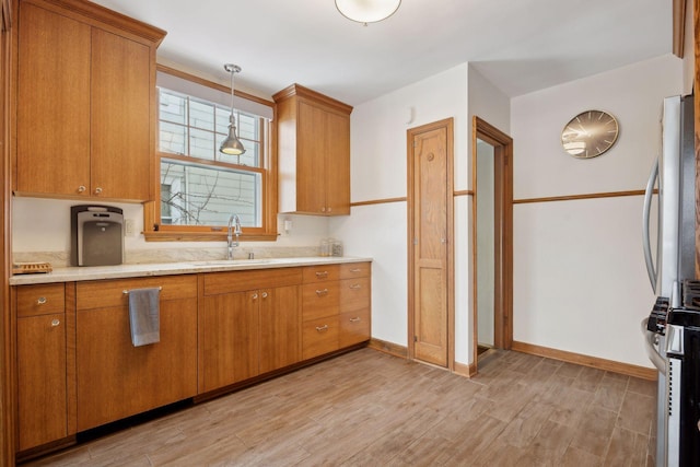 kitchen featuring sink, light wood-type flooring, and decorative light fixtures